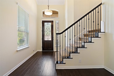 Entrance foyer with dark wood-style floors, crown molding, and a high ceiling