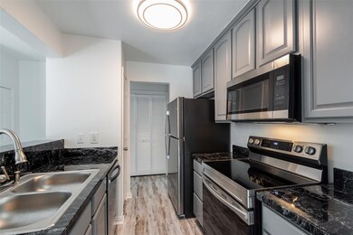 Kitchen featuring gray cabinetry, sink, dark stone