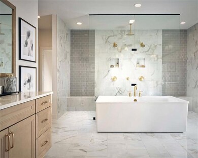 Photo from the Roswell Model Home: Full bath with marble look tile flooring, a freestanding bath, vanity, tile walls, and recessed lighting