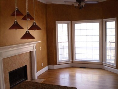 Unfurnished living room with a premium fireplace, ceiling fan, wood finished floors, and healthy amount of natural light