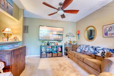 Living area with ceiling fan, carpet flooring, and a textured ceiling