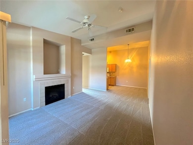 Unfurnished living room featuring carpet, a tiled fireplace, and a ceiling fan