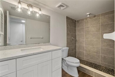 Bathroom with tiled shower, wood-type flooring, toilet, and vanity