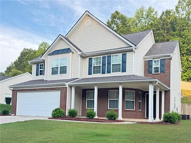 View of front of house featuring a front lawn, concrete driveway, brick siding, and a porch