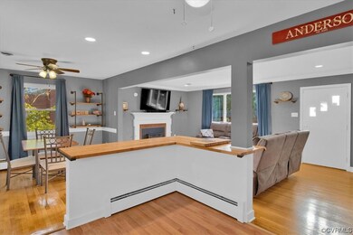 Kitchen with a fireplace, light hardwood flooring, a baseboard heating unit, and light countertops