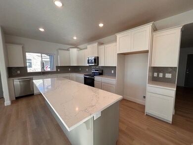 Kitchen with a kitchen island, stainless steel appliances, a breakfast bar area, white cabinetry, and decorative backsplash