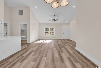 Unfurnished living room with recessed lighting, light wood finished floors, a chandelier, and high vaulted ceiling