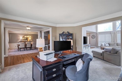 Carpeted home office featuring crown molding and a chandelier