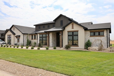 Modern farmhouse style home featuring stone siding, a standing seam roof, a front yard, a metal roof, and a shingled roof