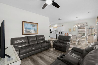 Living room featuring wood finished floors, ceiling fan, and a chandelier