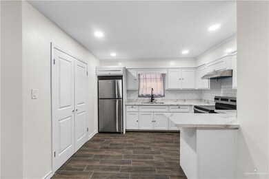 Kitchen featuring stainless steel appliances, a sink, under cabinet range hood, decorative backsplash, and recessed lighting