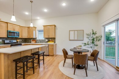 Kitchen featuring light countertops, a kitchen breakfast bar, stainless steel appliances, hanging light fixtures, and tasteful backsplash