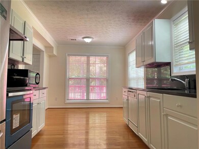 Kitchen with a sink, light wood-type flooring, dark countertops, wall oven, and crown molding