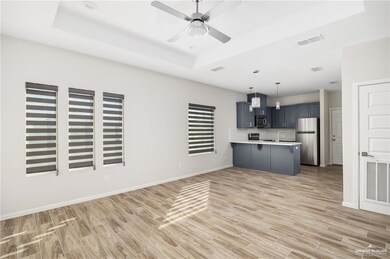 Kitchen with a raised ceiling, light countertops, visible vents, freestanding refrigerator, and a peninsula