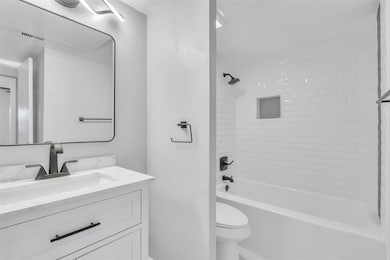 Full bathroom featuring vanity, toilet, and tiled 