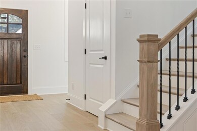 Entrance foyer featuring baseboards, stairway, and light wood finished floors