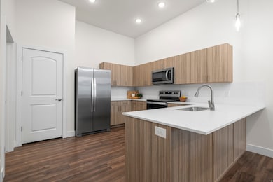 Elevated kitchen with mid-tone cabinets, quartz counters, tile backsplash, and stainless steel appliances. *Refrigerator not included.