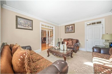 Living room with crown molding, baseboards, carpet flooring, and ornate columns