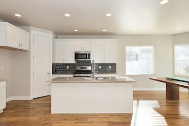 Kitchen with light stone counters, recessed lighting, decorative backsplash, stainless steel appliances, and white cabinets