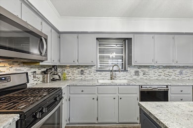 Kitchen featuring gray cabinets, tasteful backspla