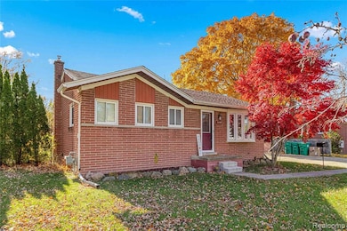 View of front facade featuring brick siding, a front yard, and a chimney