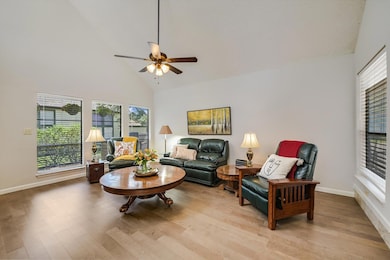 Living room featuring high vaulted ceiling, light wood-type flooring, plenty of natural light, and a ceiling fan