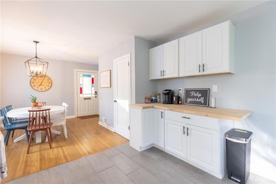 Kitchen featuring wood tiled floors, a chandelier, white cabinets, and decorative light fixtures