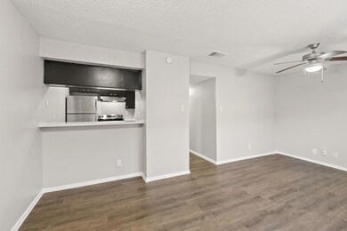 Unfurnished living room featuring dark wood-type flooring, a ceiling fan, and a textured ceiling