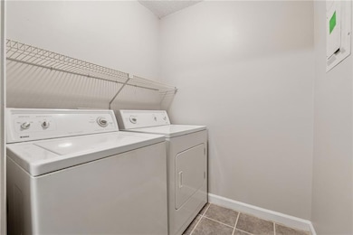 Washroom with independent washer and dryer and light tile patterned floors