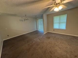 Living room featuring a chandelier, dark carpet, a textured ceiling, and ceiling fan