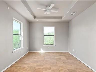 Spare room featuring plenty of natural light, a raised ceiling, and baseboards