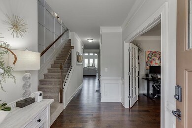 Entryway with dark wood finished floors, stairway, and ornamental molding