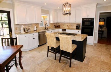 Gorgeous Remodeled Eat-in Chefs Kitchen with Custom Tile Floors, Tile Backsplash and Granite Countertops! Large Island with Cooktop and Doors leading out to the Deck and in-ground Pool! Built in Pantry with pull-outs and an Abundance of Counter space