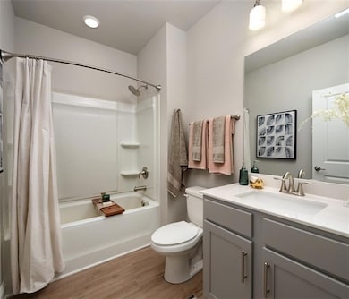 Bathroom with shower / bath combo, light wood-style flooring, and vanity
