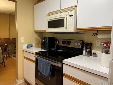 Kitchen with stainless steel electric stove, white microwave, light countertops, and white cabinetry