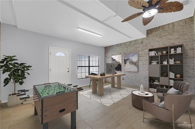 Recreation room featuring ceiling fan, an accent wall, brick wall, and light tile patterned flooring