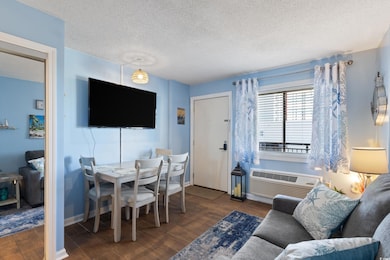 Living/Dining area with dark wood-style floors and an AC wall unit
