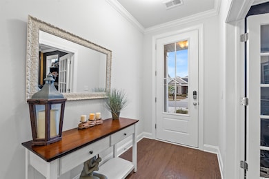 Entryway featuring ornamental molding and dark woo