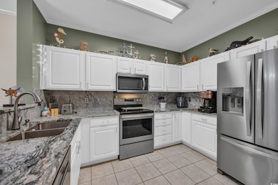 Kitchen featuring a sink, white cabinets, light ti
