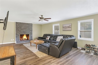 Living room with crown molding, wood finished floors, plenty of natural light, and a large fireplace