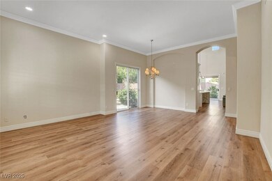 Spare room with a healthy amount of sunlight, light wood-type flooring, a notable chandelier, and arched walkways