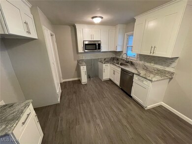 Kitchen with white cabinets, appliances with stainless steel finishes, sink, and light stone countertops