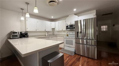 Kitchen featuring stainless steel appliances, a peninsula, dark wood finished floors, light countertops, and recessed lighting