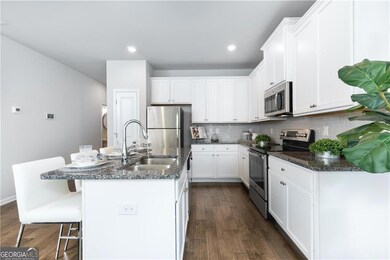 Kitchen featuring appliances with stainless steel finishes, dark wood-style floors, a kitchen bar, white cabinets, and recessed lighting