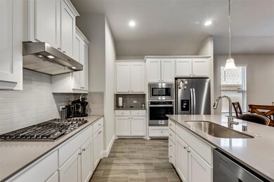 Kitchen featuring hanging light fixtures, white cabinetry, appliances with stainless steel finishes, and sink