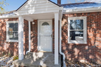 Property entrance featuring brick siding, a shingled roof, and a porch
