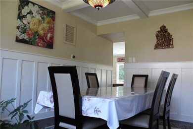 Dining space with a decorative wall, beamed ceiling, crown molding, and wainscoting