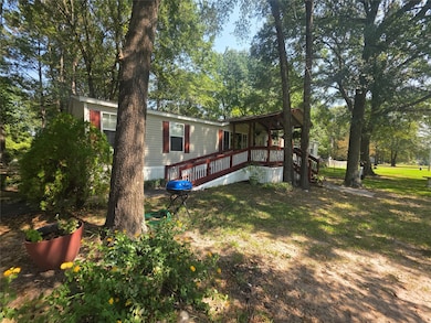 View of front of property with a front lawn, a deck, and view of scattered trees