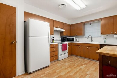 Kitchen with sink, light wood-type flooring, and white appliances