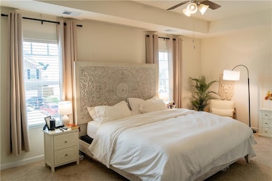 Bedroom with light carpet and multiple windows